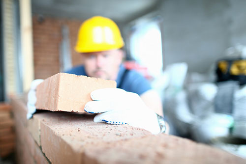 Männer in Warnwesten stehen auf einer Baustelle und sehen sich Pläne an.