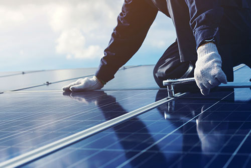 Monteur schraubt an einem Solarmodul.
