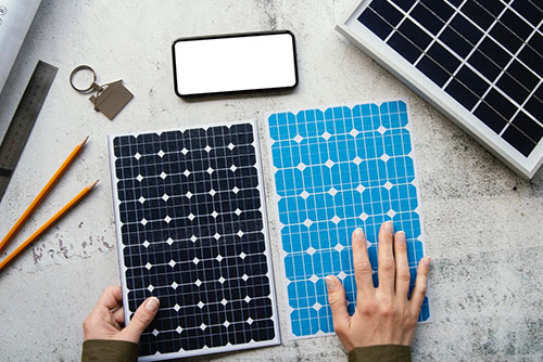 Zwei Hände halten Modelle von Solarmodulen auf einem Schreibtisch
